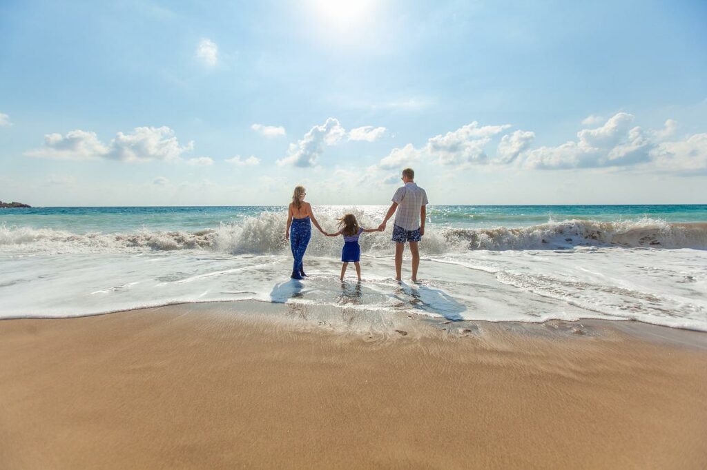Vater Mutter und Tochter am Strand Familienurlaub Das sollten Sie einpacken