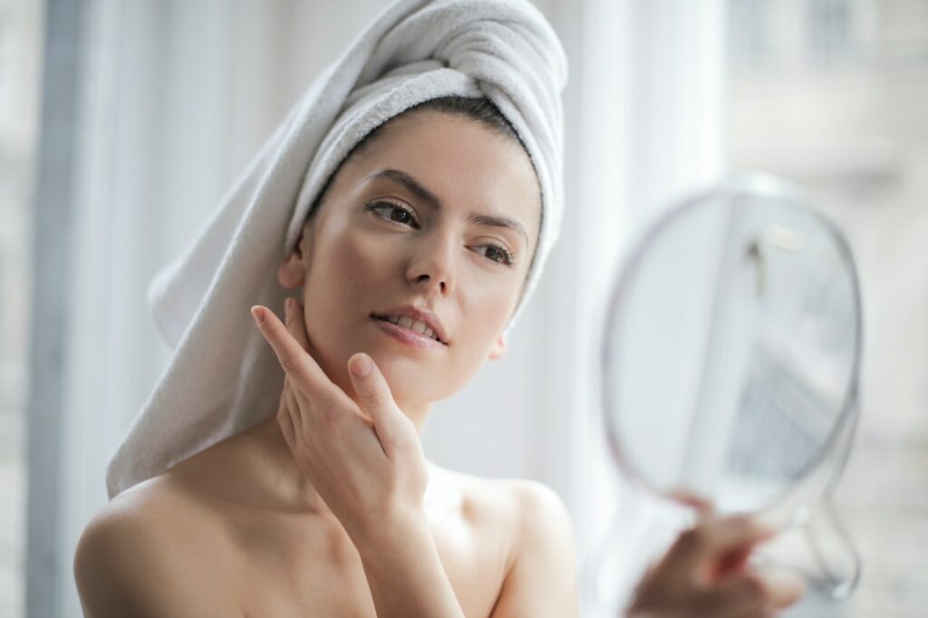 Frau betrachtet sich im Spiegel Hautpflege Welcher Hauttyp braucht welche Pflege
