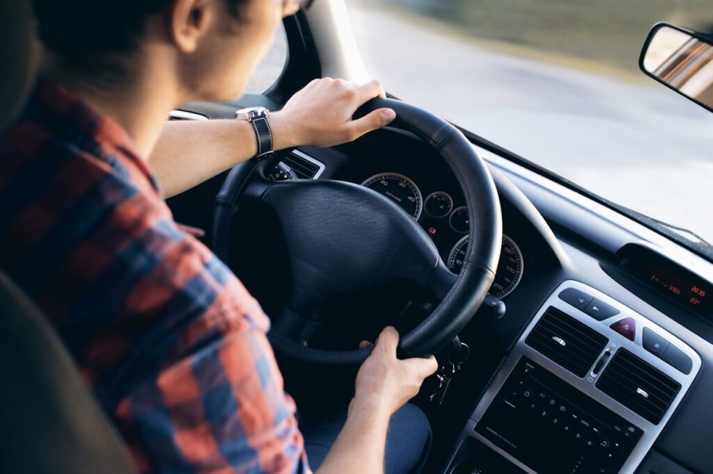 Mann sitzt im Auto Erstes eigenes Auto – Sicher unterwegs auf den Straßen