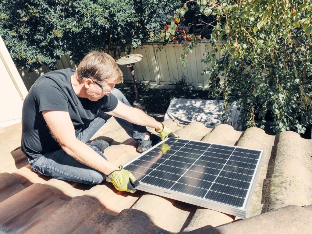 Mann baut Solaranlage auf dem Dach an Solaranlagen Kommt der Trend ins Wanken